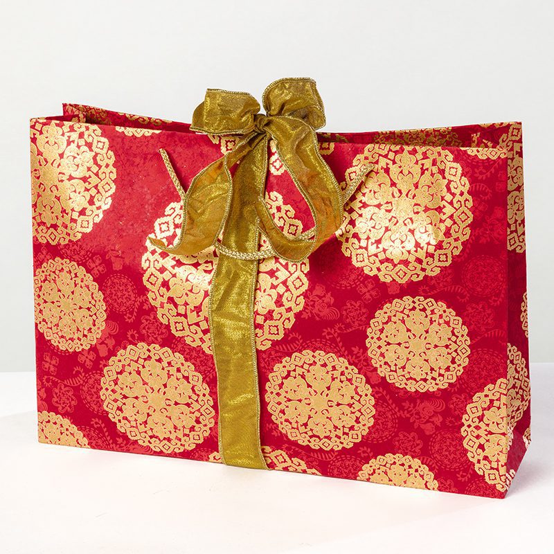 The red medallion shopper gift bag was inspired by Venetian art. The intricate background print gives richness to the gold medallions.